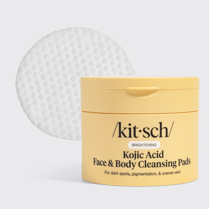 KITSCH Kojic Acid Face & Body Cleansing Pads — hero product shot on light gray background — yellow tub with single white pad displayed — BRIGHTENING | For dark spots, pigmentation, & uneven skin — Kojic Acid helps fade dark spots, reduce sun damage, and lighten acne scars — Turmeric Root Powder fights dullness and boosts antioxidants — Contains 50 pads