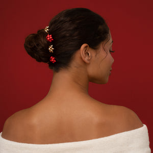 KITSCH Red & Gold Metal Gift Bow Bobby Pins 4pc Set — back view of the bow pins tucked into a low bun — Keeps hair securely in place with a comfortable hold — all-day holiday wear