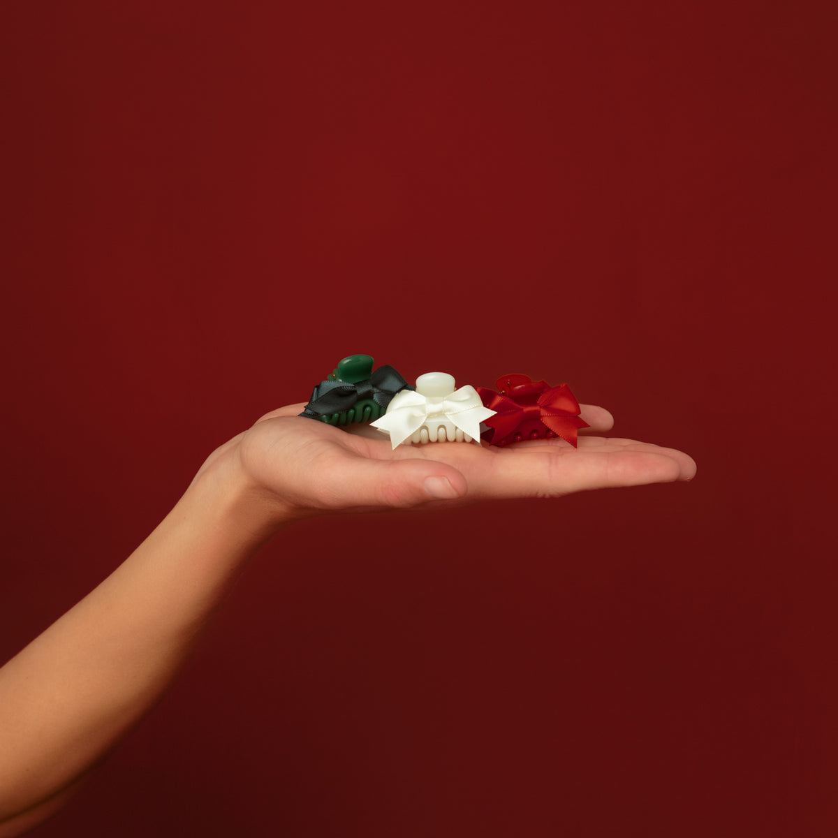 KITSCH Holiday Claw Clips 6pc Set - Mini — open palm holding a red, an ivory and a green mini claw clip — Six cheerful mini claw clips in classic holiday colors for mixing and matching — gifting