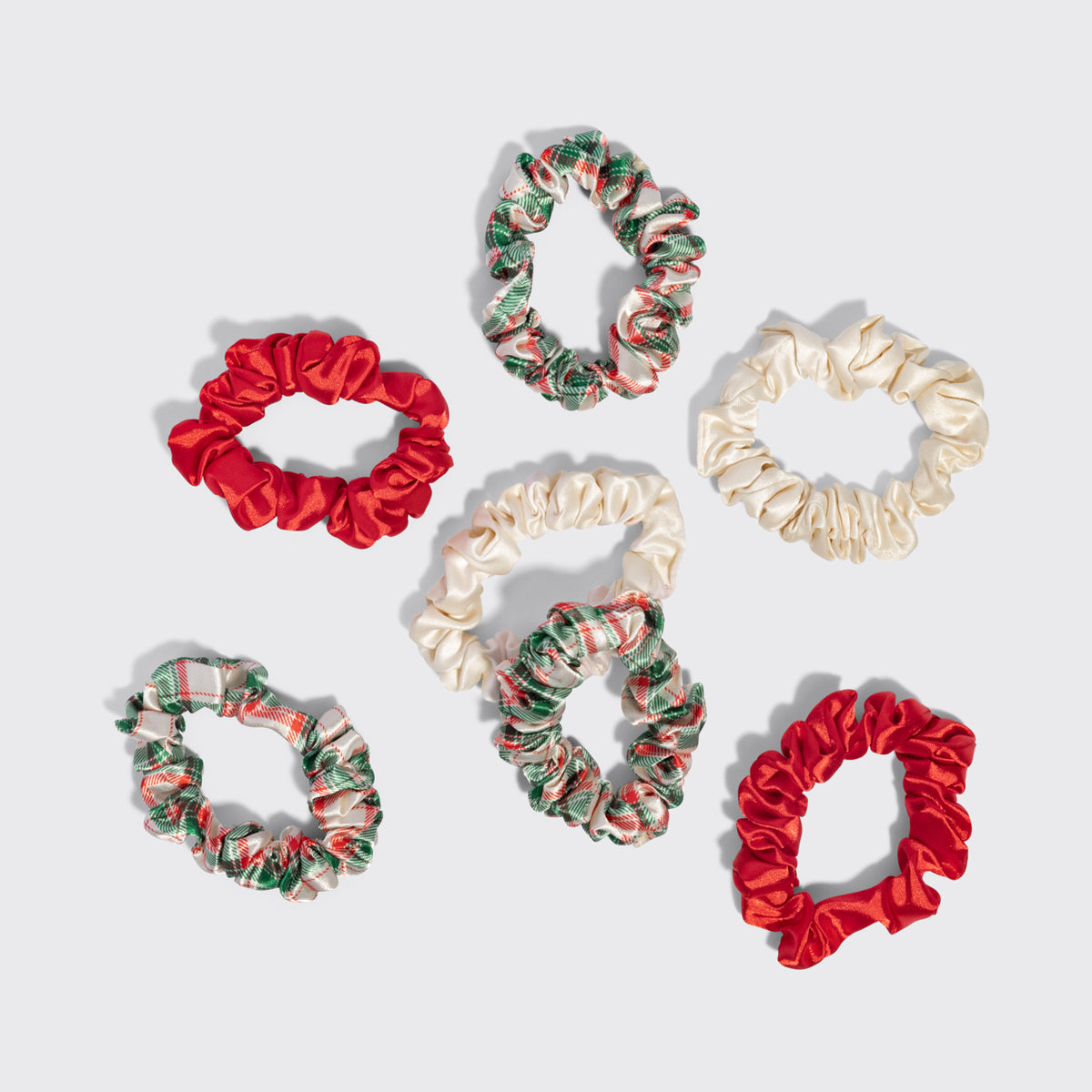 KITSCH Holiday Ruched Satin Scrunchies 7pc Set — all seven scrunchies laid out separately on a grey background — Creaseless design helps protect hair from breakage — everyday styling