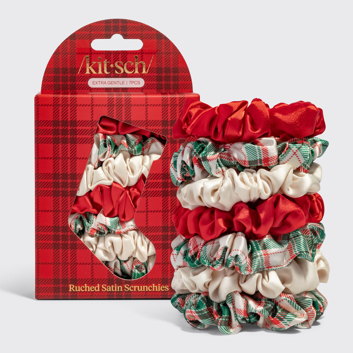 KITSCH Holiday Ruched Satin Scrunchies 7pc Set — stacked plaid, ivory and red satin scrunchies beside the stocking-print packaging box — Silky material protects hair while you sleep or style — holiday hairstyles